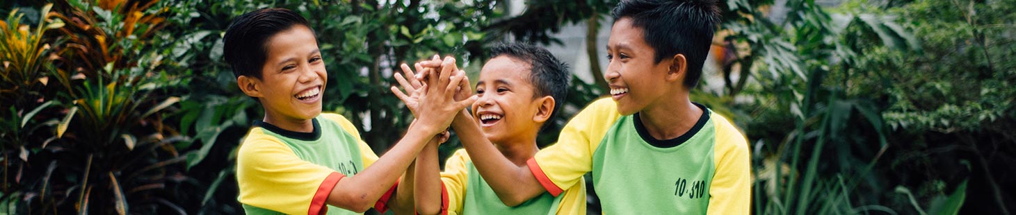 Three boys laughing and clasping hands