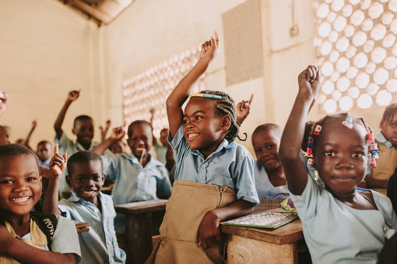 Children eagerly raise their hands in the classroom