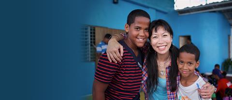 A woman stands with two sponsored children