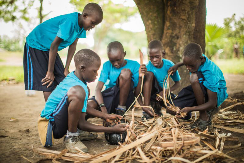 Boys make a soccer ball out of strips of plants