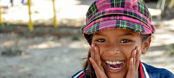 A girl wearing a plaid hat cups her hands by her mouth