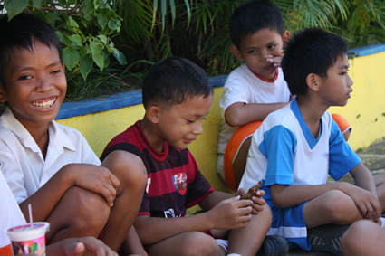 four boys sitting on a sidewalk