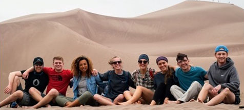 Compassion group posing in front of sand dune