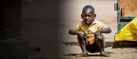 A boy wearing yellow squats on the ground