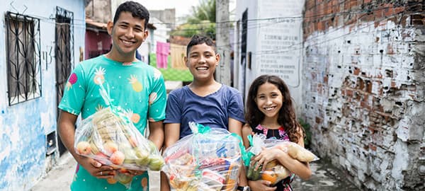 Children standing in line to receive food from a woman at a table.