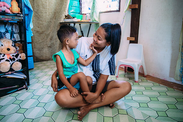 Child sitting with an adult on the floor smiling