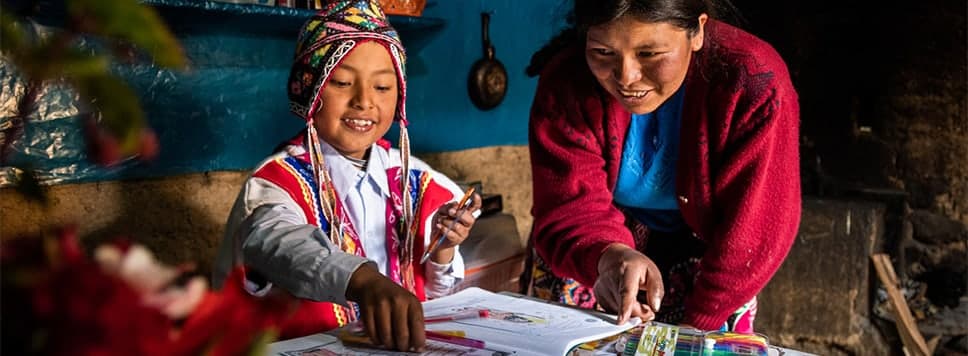 Girl and her mother working on a workbook together at a table.