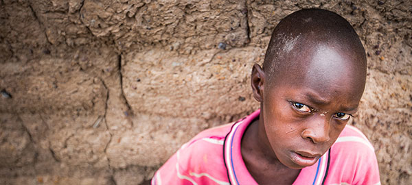 A boy in a pink polo shirt with a solemn expression 