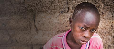 A boy in a pink polo shirt with a solemn expression 