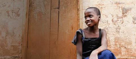 A smiling young girl in a black and blue dress