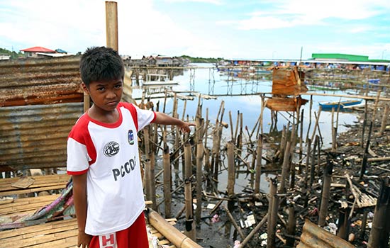 A boy points out destruction that occurred because of a natural disaster