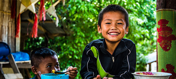 A smiling boy leans on his elbows on a table