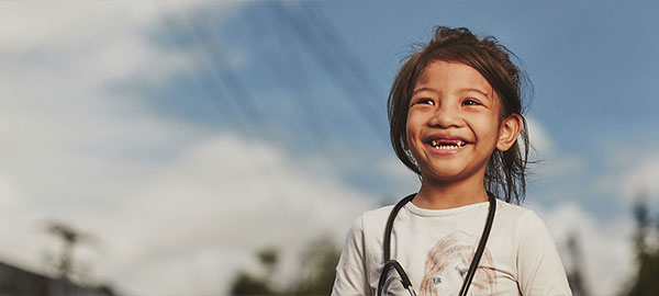 A smiling girl in a white shirt with a stethoscope around her neck