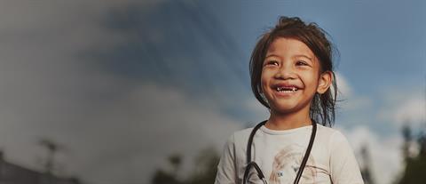 A smiling girl in a white shirt with a stethoscope around her neck