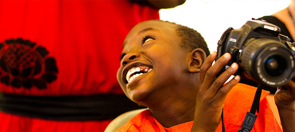 A boy in a red shirt holding a camera