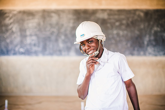 A boy wearing a white t-shirt and a white construction hard hat