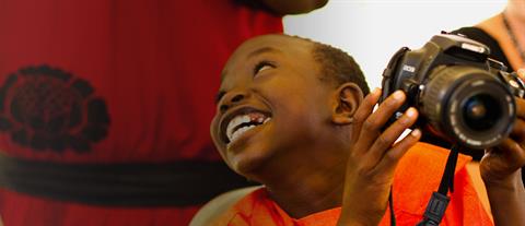 A boy in a red shirt holding a camera