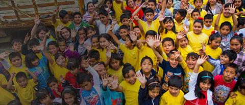 A large group of children waving hello