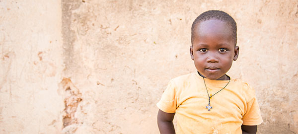 A boy in a yellow shirt with a serious expression