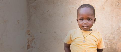 A boy in a yellow shirt with a serious expression