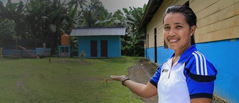 A woman directs attention to a hygienic toilet facility