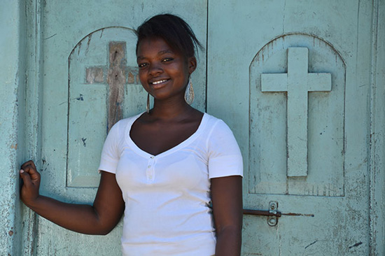 Girl standing in front of a blue door with crosses on it