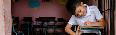 A boy sits to write a letter