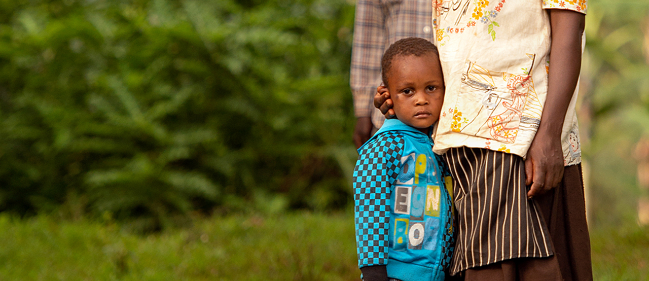 A young boy stands with a parent